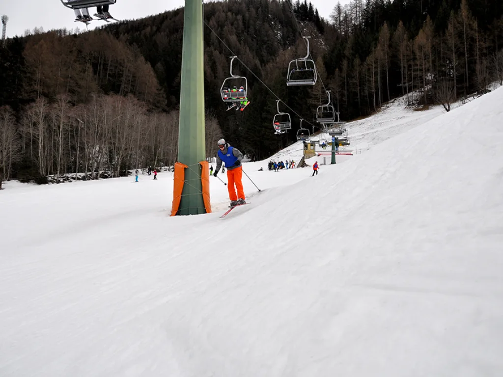 Skifahrer in oranger Hose auf der Piste unter dem Lift.